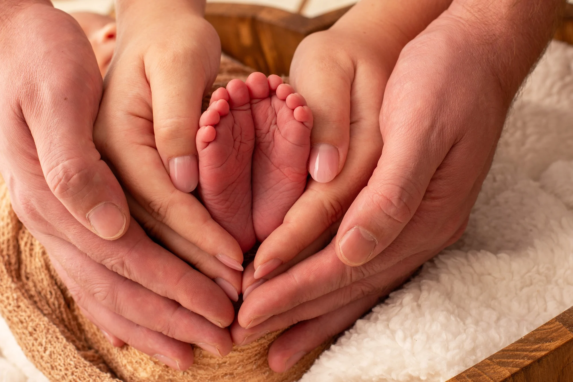 Die Hände der Eltern umschließen die kleinen Füße ihres Babys